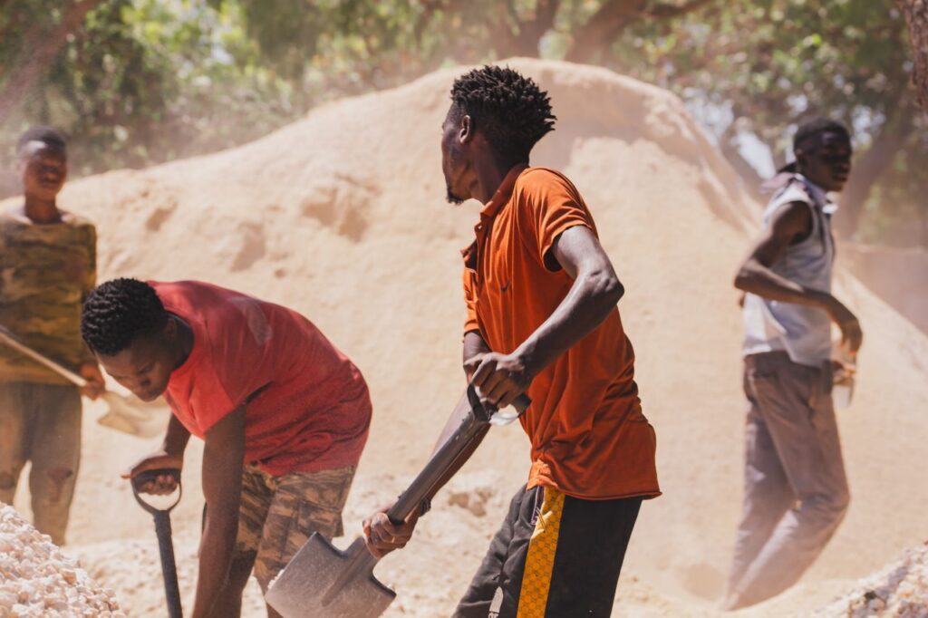 A group of men collaborating on labor tasks with shovels outdoors.