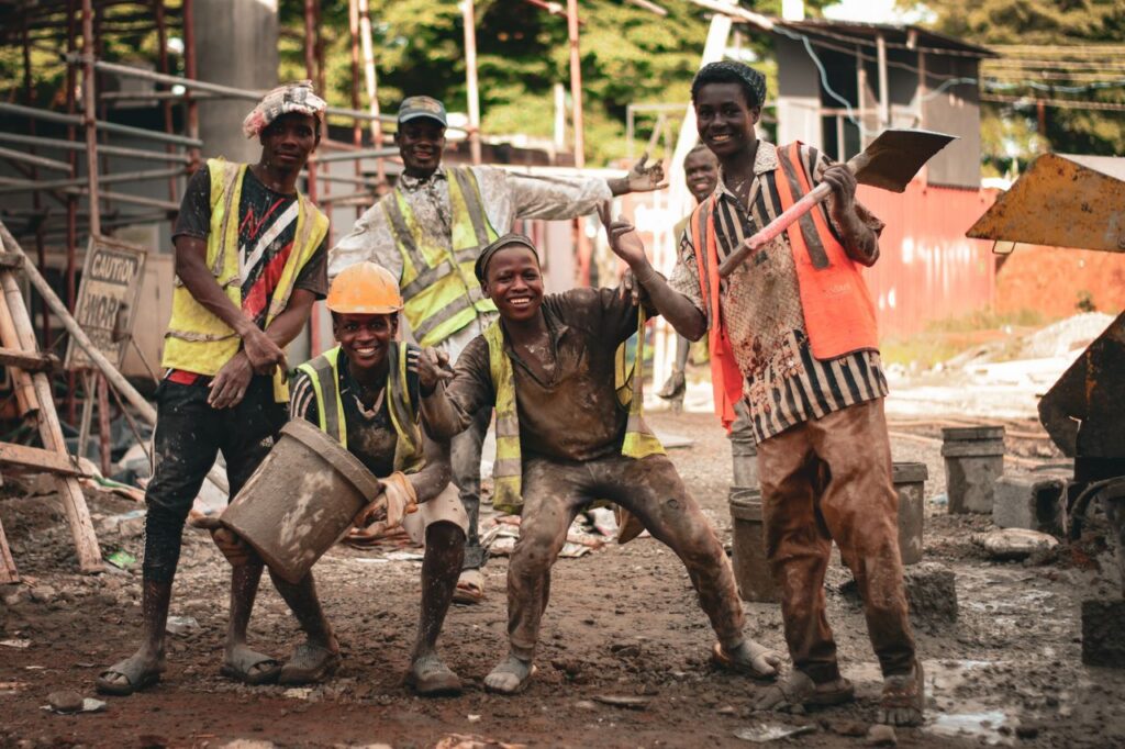 Group of construction workers in high spirits at an outdoor construction site.